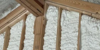 Wooden beams and studs with expanding spray foam insulation applied between them