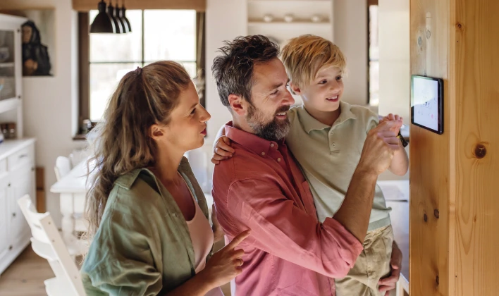 Young family looking at digital thermostat in a home.
